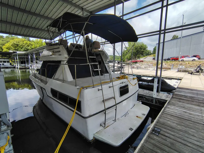 Slide: The Image of 1994 Carver 300 boat docked under a covered marina, featuring a spacious deck and canopy. - 9