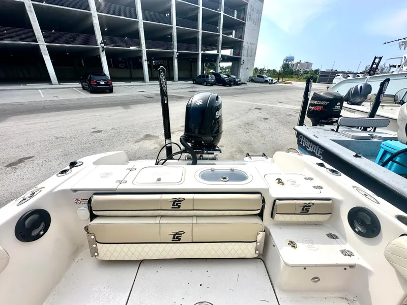 Slide: The Image of 2022 Carolina Skiff 23 Ultra Elite boat interior with storage compartments and outboard motor. - 9