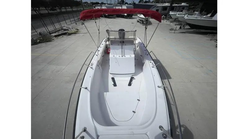 Slide: The Image of 1997 Boston Whaler OUTRAGE boat with red canopy, docked on concrete surface. - 3