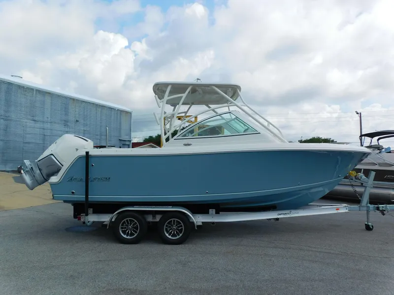 The Image of 2025 Sailfish 245 DC boat on trailer, blue hull, parked outdoors. - 0