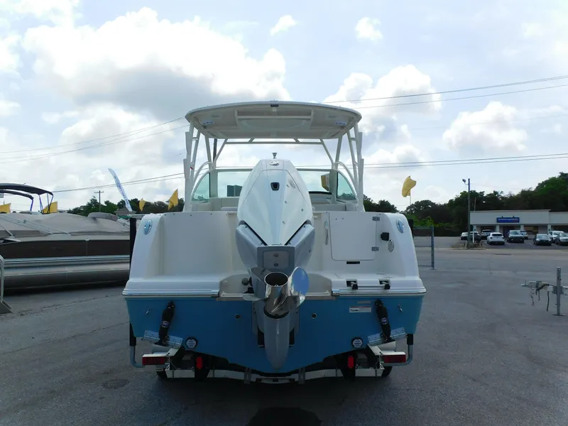 Slide: The Image of 2025 Sailfish 245 DC boat, rear view, parked outdoors under cloudy sky. - 2