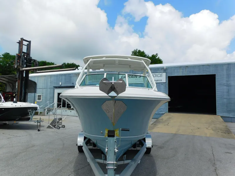 Slide: The Image of 2025 Sailfish 245 DC boat on trailer, parked outside a metal building under a cloudy sky. - 34