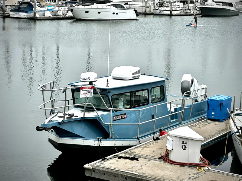 Slide: The Image of Blue ACB 30 boat docked in marina, 2003 model, surrounded by other vessels. - 2