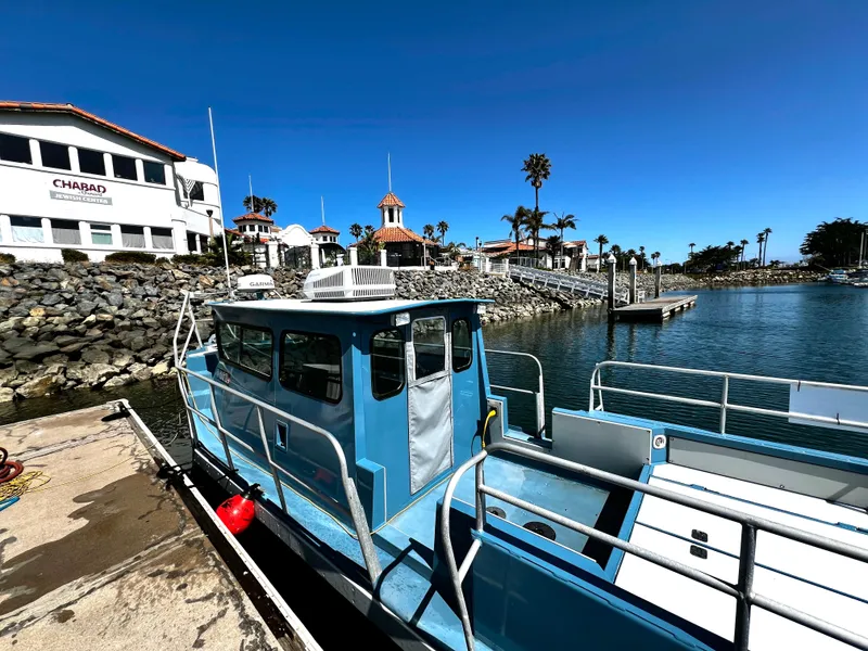 Slide: The Image of Blue ACB 30 boat docked near a waterfront building, clear sky, 2003 model. - 7