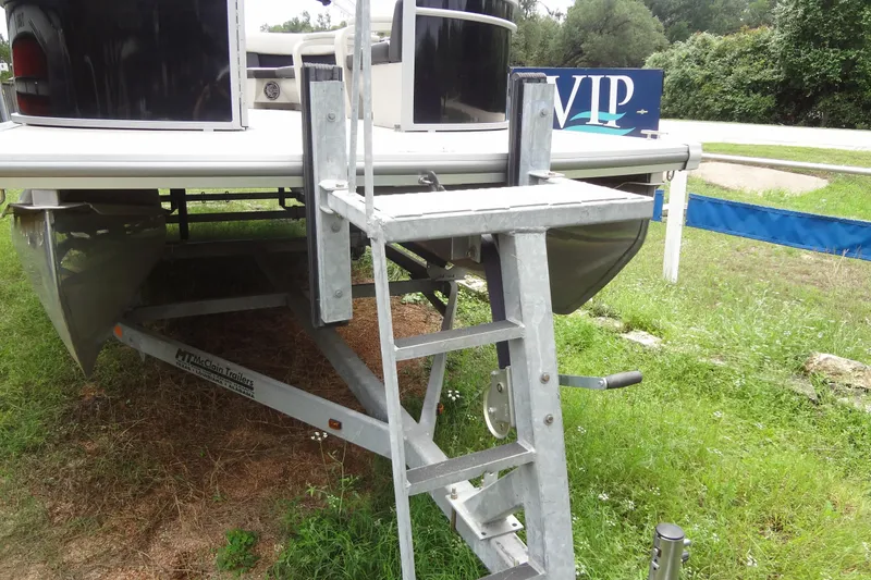 Slide: The Image of 2024 Harris FloteBote 210 Breeze pontoon boat on trailer with metal ladder, parked on grass. - 30