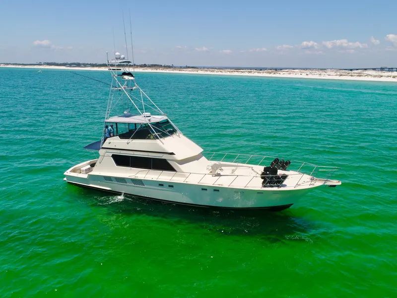 Slide: The Image of 1987 Hatteras 65 Convertible yacht on turquoise waters near sandy shoreline. - 0