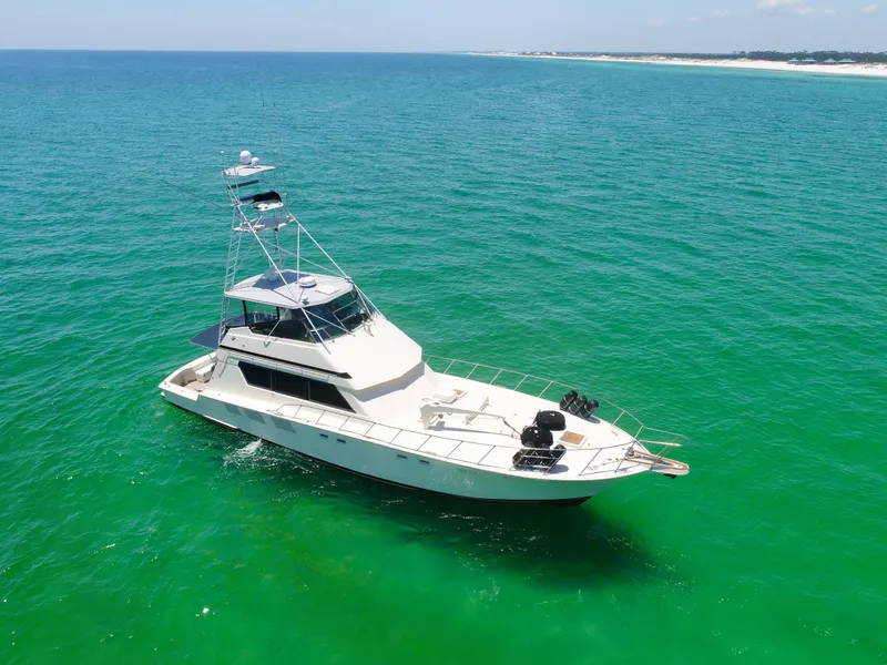 Slide: The Image of 1987 Hatteras 65 Convertible yacht on clear turquoise water, aerial view. - 10