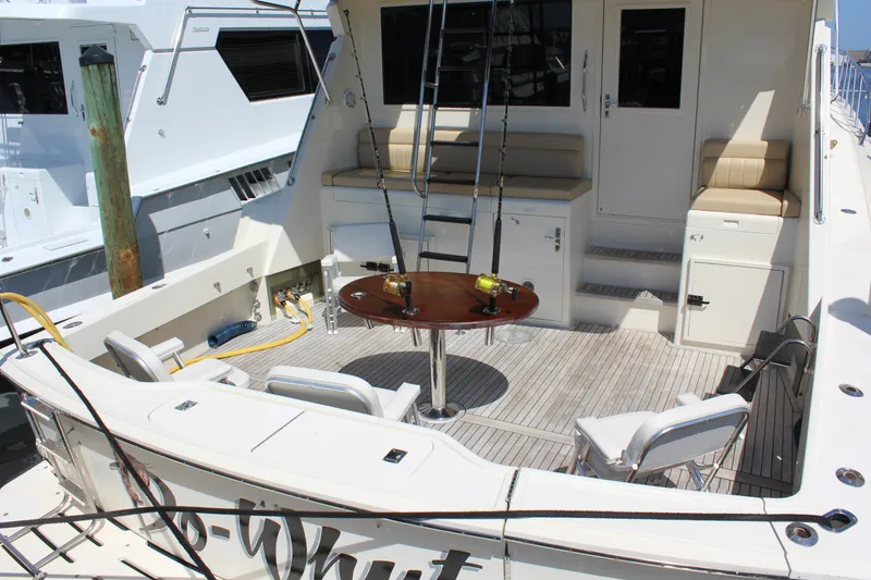 Slide: The Image of 1987 Hatteras 65 Convertible yacht deck with fishing rods and seating area. - 11