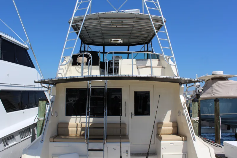 Slide: The Image of 1987 Hatteras 65 Convertible yacht with upper deck and seating, docked at marina. - 13