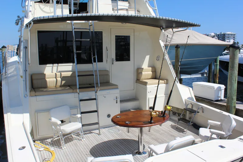 Slide: The Image of 1987 Hatteras 65 Convertible yacht deck with seating, table, and fishing rod. - 16