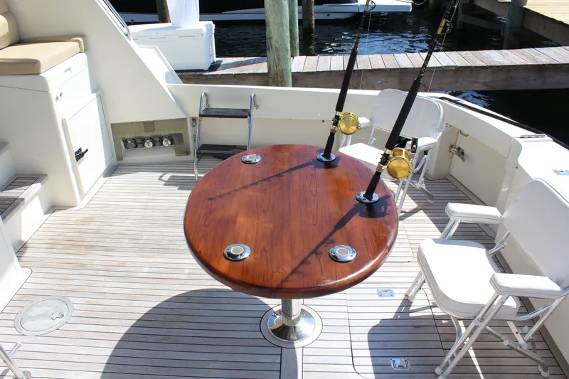 Slide: The Image of 1987 Hatteras 65 Convertible yacht deck with fishing rods and seating. - 25