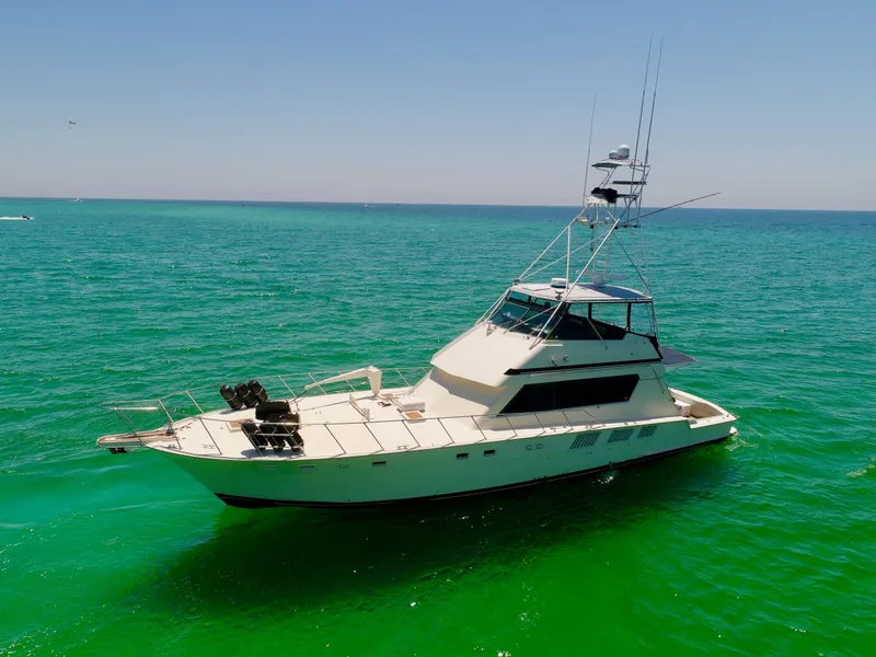 Slide: The Image of 1987 Hatteras 65 Convertible yacht on clear turquoise water under a bright blue sky. - 3