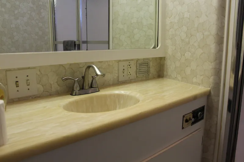 Slide: The Image of Bathroom sink area in 1987 Hatteras 65 Convertible yacht, featuring a marble countertop and modern faucet. - 34