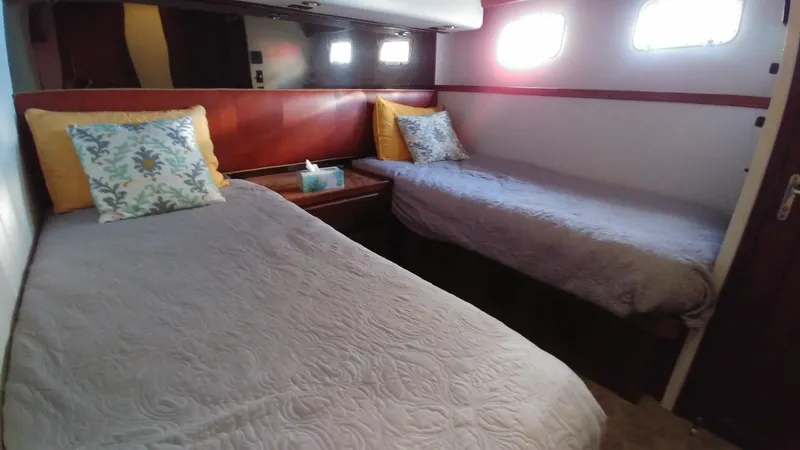 Slide: The Image of 1987 Hatteras 65 Convertible cabin with twin beds and decorative pillows. - 35