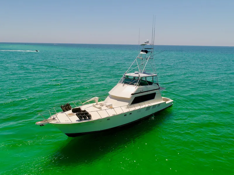 Slide: The Image of 1987 Hatteras 65 Convertible yacht cruising on clear turquoise waters. - 4