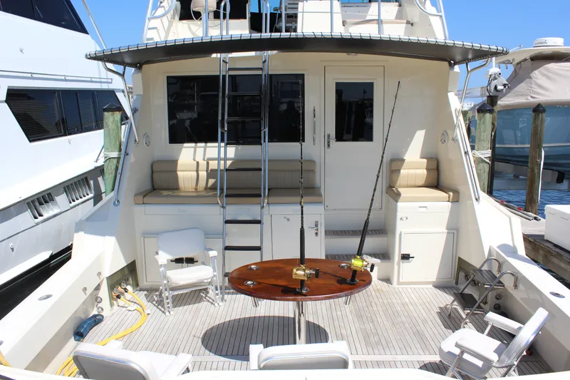 Slide: The Image of 1987 Hatteras 65 Convertible yacht deck with seating, fishing rods, and table. - 8