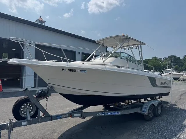 Slide: The Image of 1995 Pro-Line 231 WA boat on trailer, parked outdoors near a building. - 2