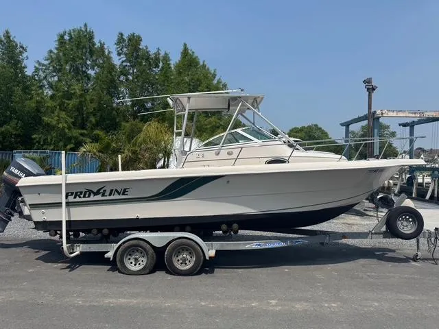 Slide: The Image of 1995 Pro-Line 231 WA boat on trailer, parked outdoors, with trees in the background. - 3