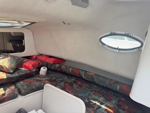 Slide: The Image of Interior cabin of a 1995 Pro-Line 231 WA boat with patterned cushions and a small porthole window. - 8