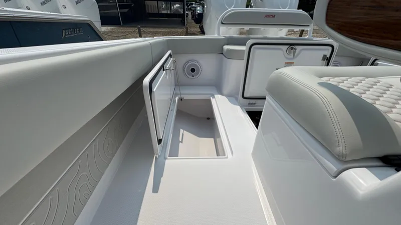 Slide: The Image of 2026 Jupiter 32 boat interior with open storage compartment and cushioned seating. - 15