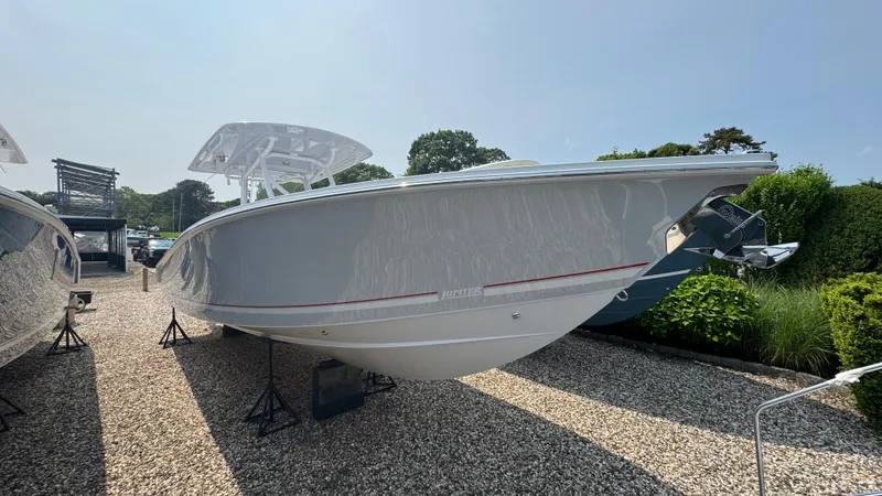Slide: The Image of 2026 Jupiter 32 boat displayed outdoors on gravel, side view. - 2