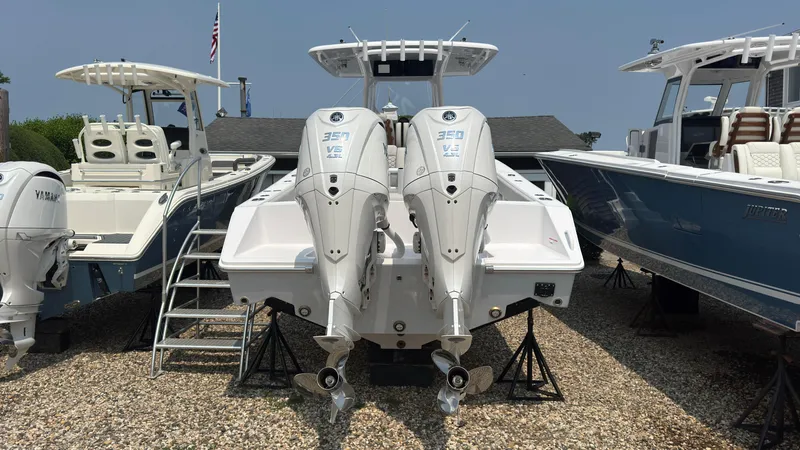 Slide: The Image of 2026 Jupiter 32 boat with dual outboard engines displayed on gravel lot. - 3