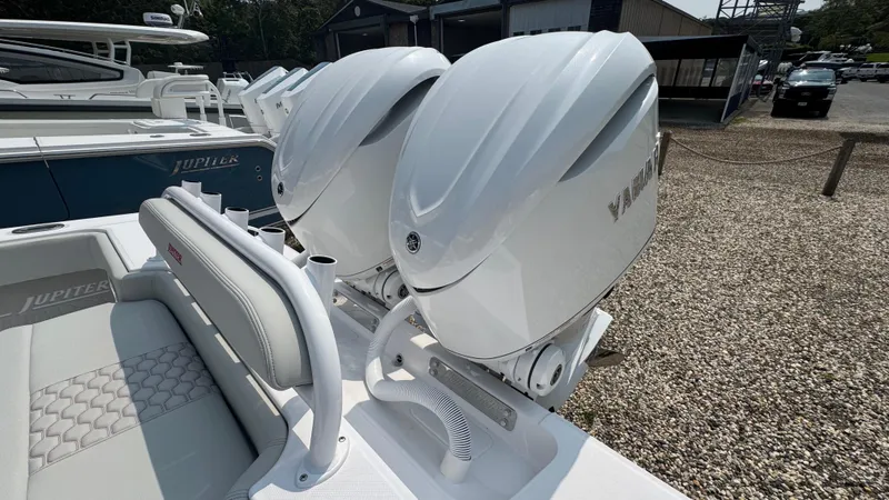 Slide: The Image of 2026 Jupiter 32 boat with dual Yamaha outboard engines, parked on gravel. - 6