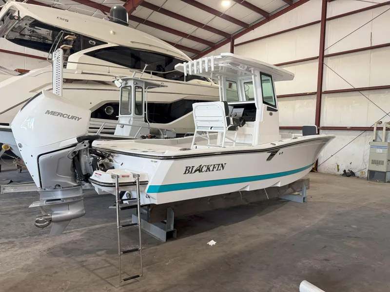 The Image of 2026 Blackfin 242HB boat in a warehouse, featuring a Mercury engine. - 0