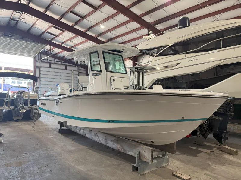 Slide: The Image of 2026 Blackfin 242HB boat in a showroom, side view, under a metal roof. - 2