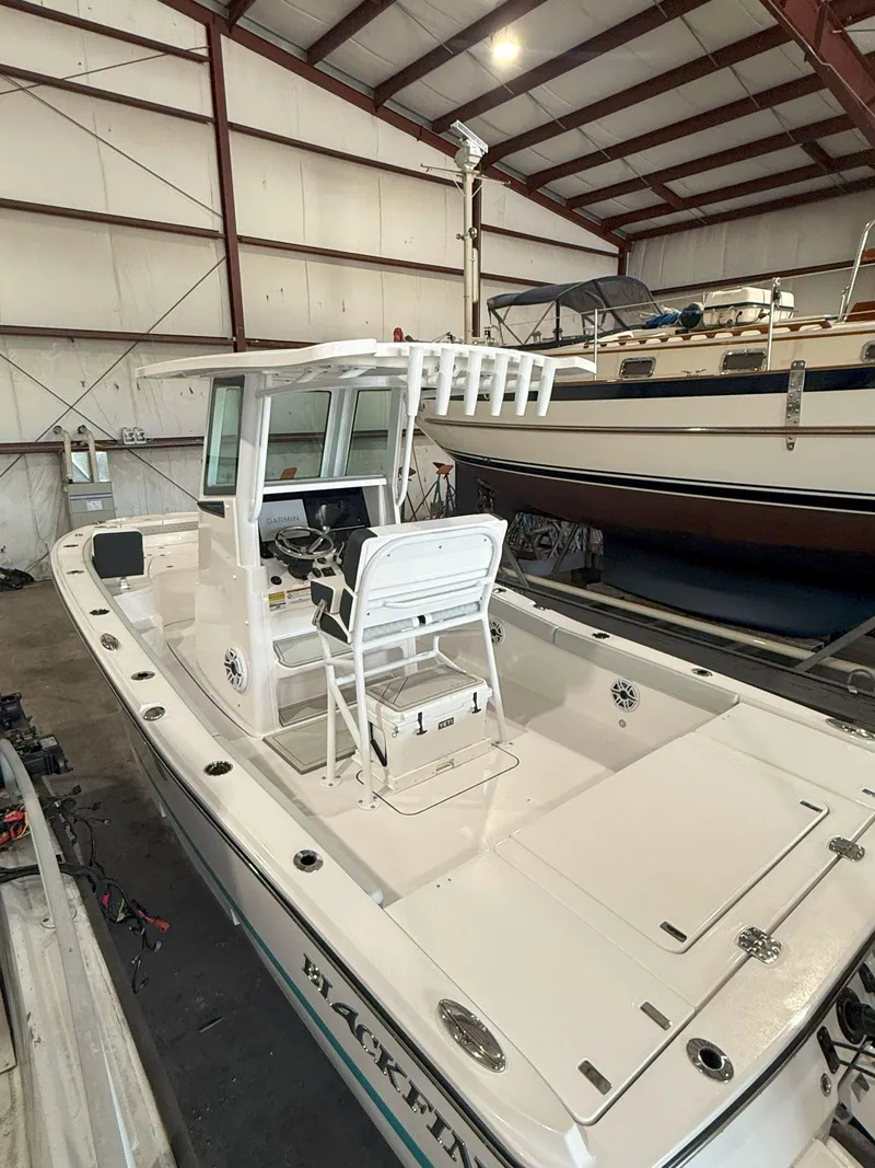 Slide: The Image of 2026 Blackfin 242HB boat in storage, featuring a center console and rod holders. - 5