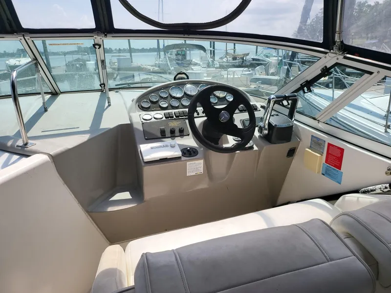 Slide: The Image of 2004 Cruisers 280CXi boat cockpit with steering wheel and control panel, docked at marina. - 2