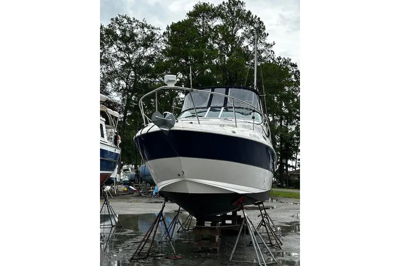 Slide: The Image of 2004 Cruisers 280CXi boat on stands, surrounded by trees and overcast sky. - 21