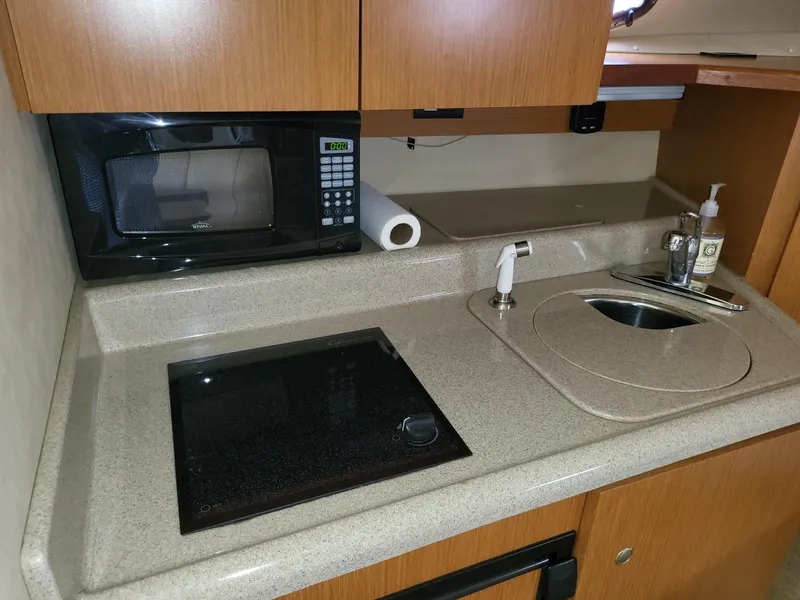 Slide: The Image of 2004 Cruisers 280CXi boat kitchenette with microwave, stovetop, and sink. - 7