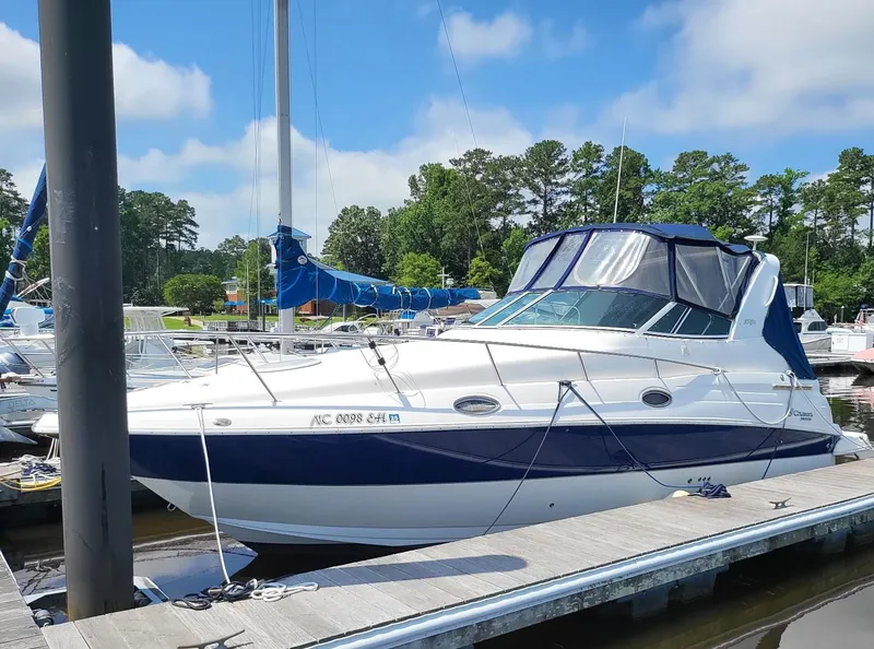 Slide: The Image of 2004 Cruisers 280CXi boat docked at marina, surrounded by trees and clear sky. - 14