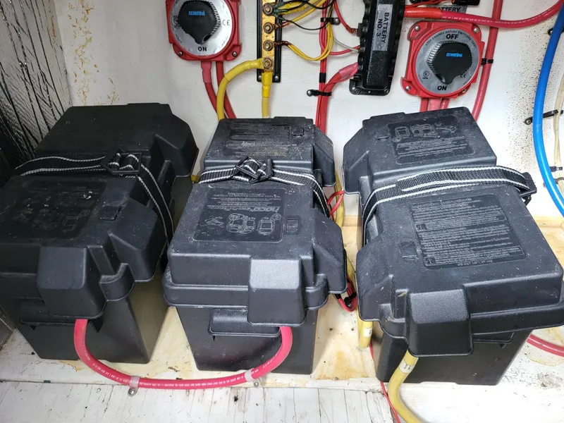 Slide: The Image of Four marine batteries in a 2004 Cruisers 280CXi boat, secured with straps and connected with cables. - 17