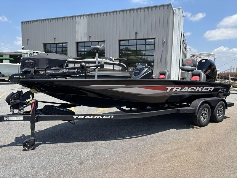 The Image of 2025 Tracker SAVAGE™ 215 boat on trailer, parked outside a building under a clear sky. - 0