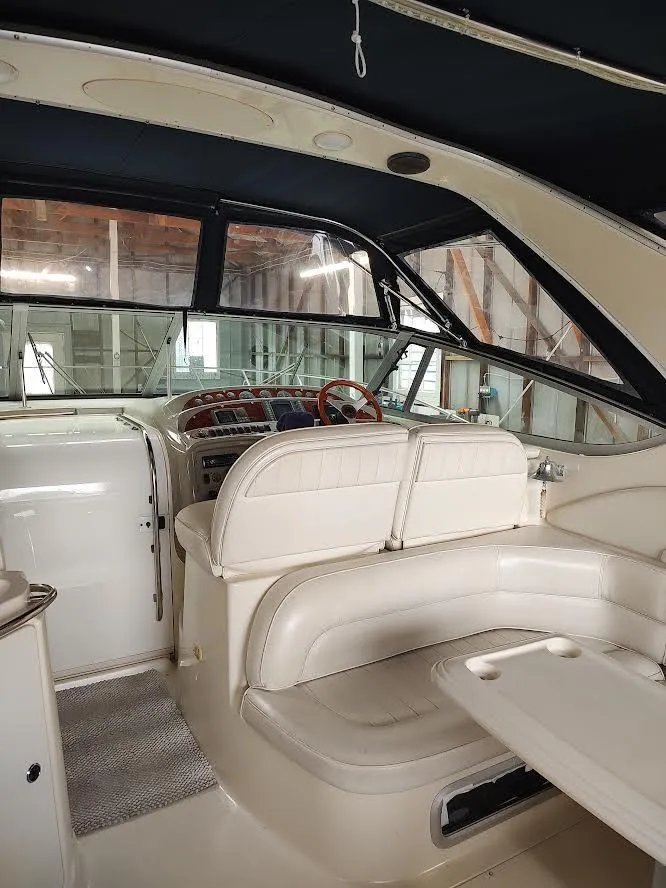 Slide: The Image of 1998 Maxum 4100 Sun Bridge SCR interior with seating and helm in a covered dock. - 12