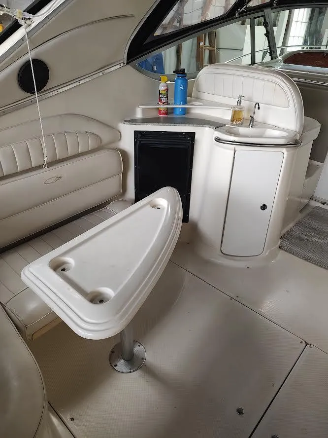 Slide: The Image of 1998 Maxum 4100 Sun Bridge SCR interior with seating, table, and mini fridge. - 15