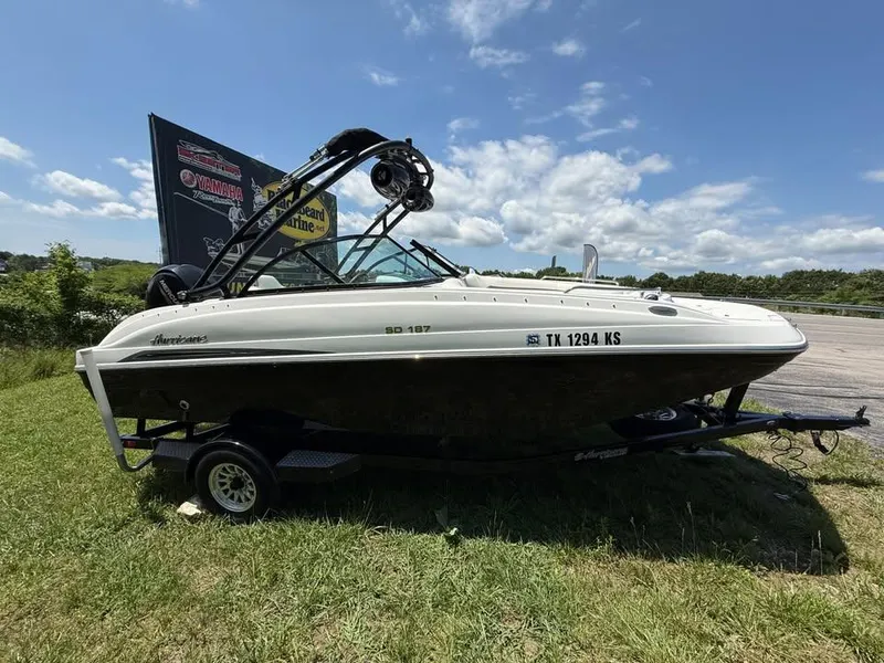Slide: The Image of 2023 Hurricane SD 187 boat on trailer, parked on grass under a clear blue sky. - 2
