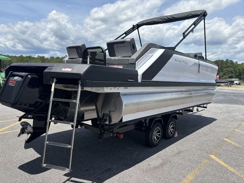 Slide: The Image of 2025 Manitou Cruise 22 Max Switchback pontoon boat with Rotax 150 engine, parked outdoors. - 4