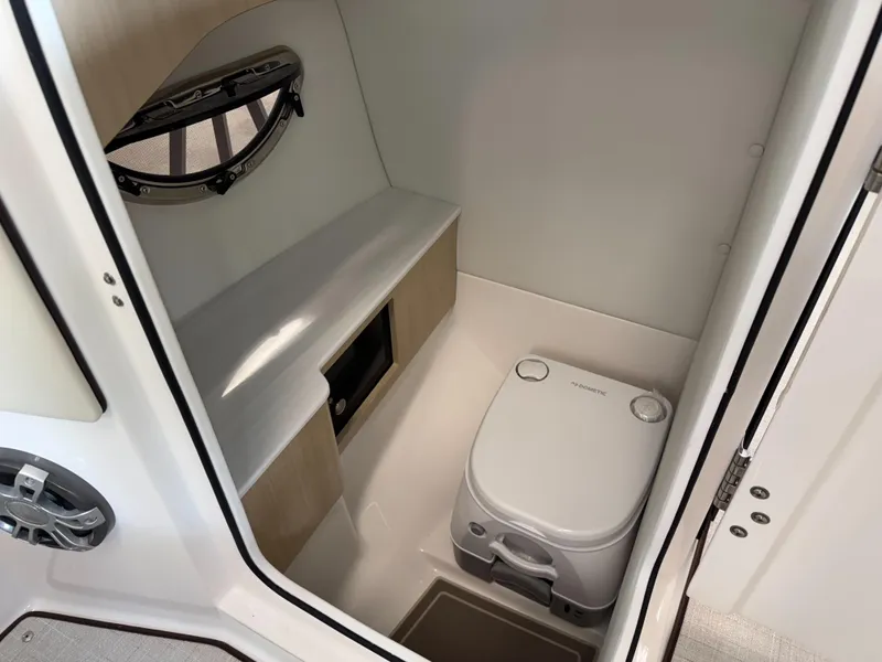 Slide: The Image of 2025 Regal LS6 boat interior bathroom with compact toilet and storage. - 14