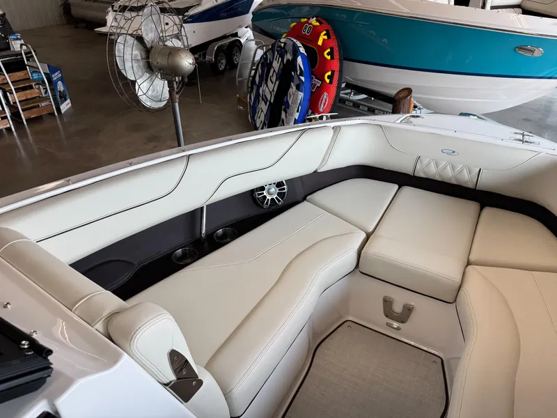 Slide: The Image of 2025 Regal LS6 boat interior with white seating and cup holders in a showroom. - 8