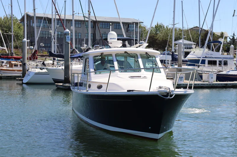 Slide: The Image of 2011 Back Cove 30 boat docked in a marina with sailboats in the background. - 2