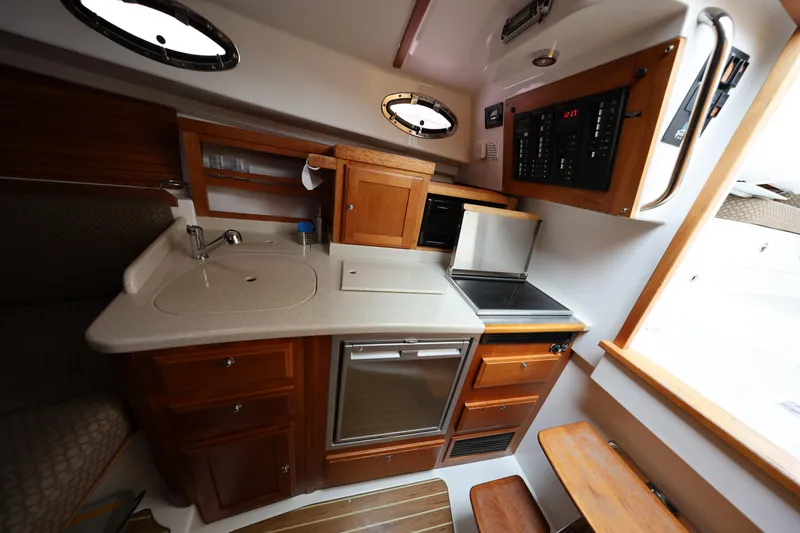 Slide: The Image of 2011 Back Cove 30 yacht interior kitchen with sink, stove, and wooden cabinetry. - 22