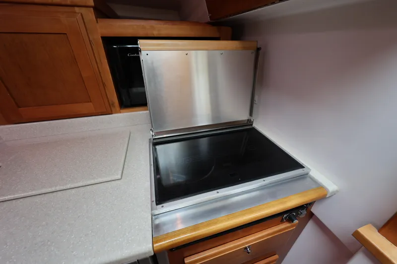 Slide: The Image of Modern kitchen area in a 2011 Back Cove 30 boat with stove and wooden cabinetry. - 23