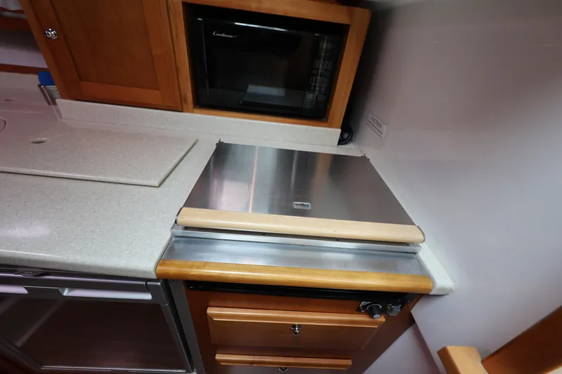 Slide: The Image of 2011 Back Cove 30 yacht kitchen with stove, microwave, and wooden cabinetry. - 24