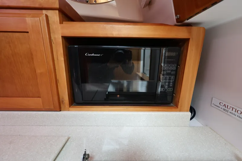 Slide: The Image of Microwave in 2011 Back Cove 30 boat kitchen, wooden cabinetry, countertop, caution sign visible. - 25