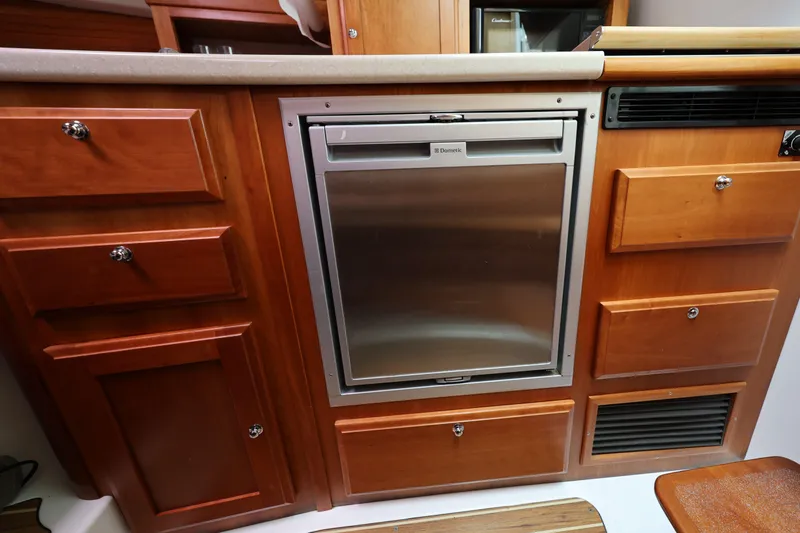Slide: The Image of 2011 Back Cove 30 yacht kitchen with wooden cabinetry and stainless steel fridge. - 26