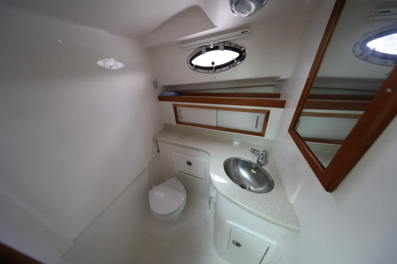 Slide: The Image of 2011 Back Cove 30 yacht bathroom with sink, toilet, mirror, and storage cabinets. - 31