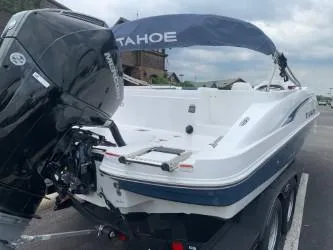 Slide: The Image of 2023 Tahoe 2150 Deck Boat with Mercury engine, parked outdoors. - 2